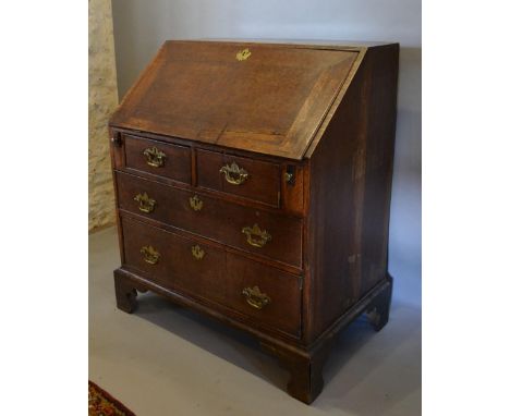 A George III Oak Bureau, the fall front enclosing a fitted interior above two short and two long drawers with brass handles a