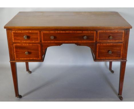 An Edwardian Mahogany Satinwood Crossbanded Writing Desk with five drawers and brass knob handles, raised upon square taperin