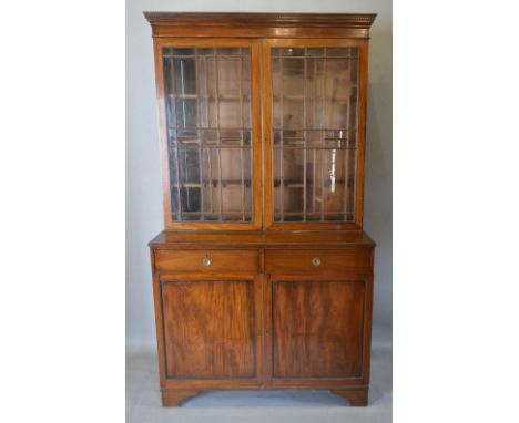 A 19th Century Mahogany Bookcase, the moulded cornice above two glazed doors enclosing shelves, the lower section with two dr