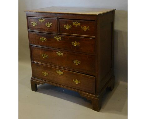 A George III Oak Chest, the moulded top above two short and three long drawers with brass handles and escutcheons raised upon