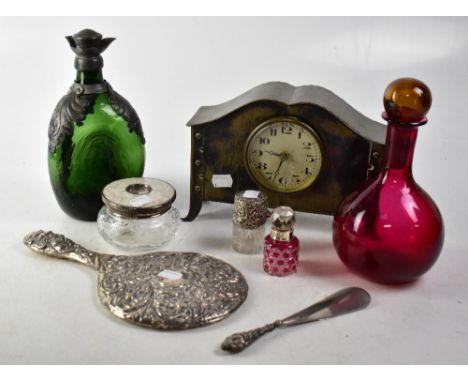 An Arts &amp; Crafts brass mantel clock, the dial set with Arabic numerals, a green glass dimple bottle with pewter mounts, a