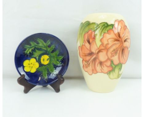 MOORCROFT; a 'Hibiscus' pattern ivory ground ovoid vase, height 19cm and a small 'Buttercup' pattern blue ground trinket dish