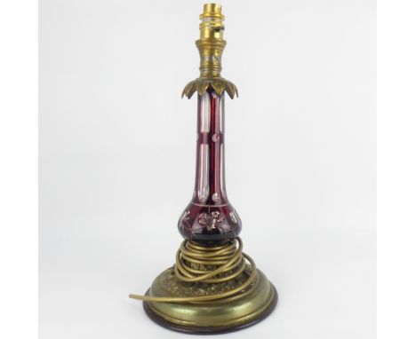 A cut glass flashed cranberry glass table lamp with brass top and acanthus leaf apron, on an oak leaf and acorn embellished b