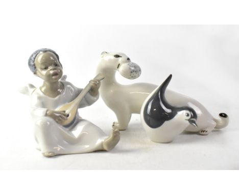 LLADRÓ; four figures comprising a penguin, a bear, an angel playing guitar and a woman seated on rocks with piglets at her fe