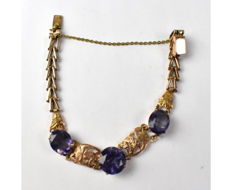 A late 19th/early 20th century rose gold bracelet set with three graduated claw set stones, synthetic corundum, on Celtic and