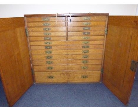 A late 19th century large floor standing oak cutlery cabinet, interior with seventeen graduated drawers to include two banks 