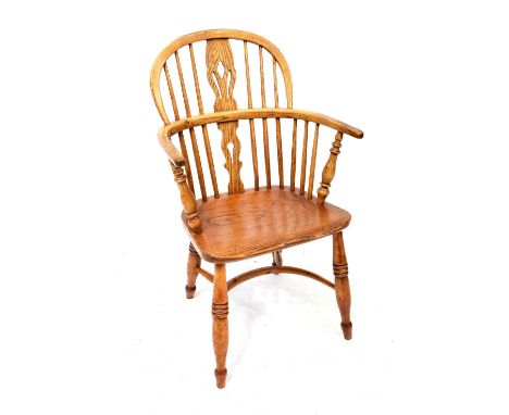 A 19th century low Windsor chair with comb back, pierced back splats, turned armrest supports, possibly elm seat and curved s
