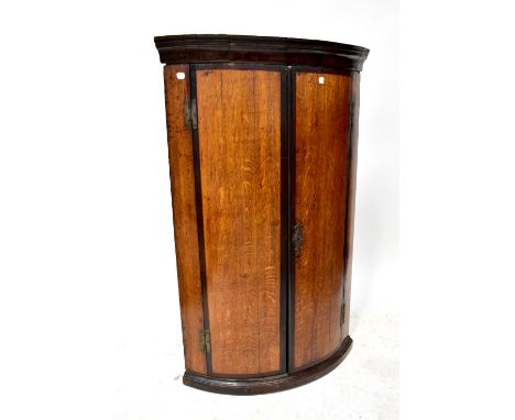 A Georgian oak and crossbanded mahogany bowed corner cupboard, 106 x 66 x 46cm. CONDITION REPORT: Top left section of the fri