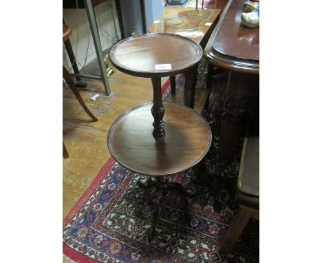 A MAHOGANY TWO TIER DUMB WAITER of circular outline each dish joined by a baluster and ring turned support and tripod base 86