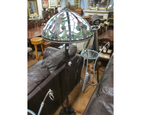 A TIFFANY STYLE FLOOR STANDARD LAMP with multicoloured glass shade above a reeded column on circular spreading foot moulded i