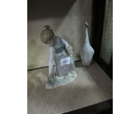 A LLADRO FIGURE modelled as a young girl shown kneeling together with a lladro figure and a duck