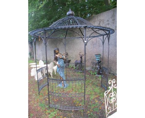 A REGENCY STYLE WROUGHT IRON GAZEBO of circular form the domed hood with coronation finial and C scroll and fleur de lis deco