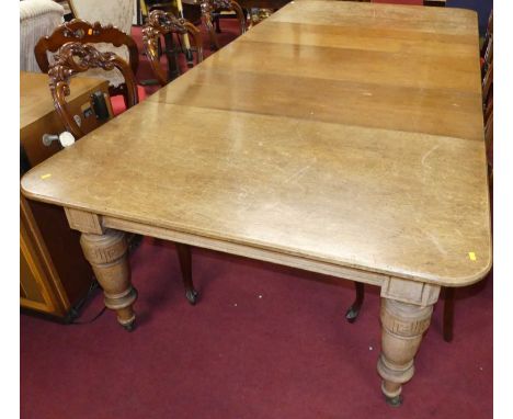 A late Victorian oak round cornered extending dining table, having a wind-out action, three extra drop-in leaves, and raised 