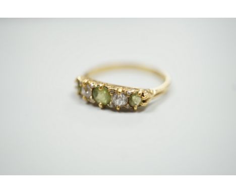 An 18ct, three stone peridot and two stone diamond set half hoop ring. size N, gross weight 2.6 grams.