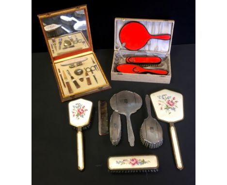 A silver backed dressing table set comprising brush, comb, hand mirror and hand brush; another two sets and a manicure set. 