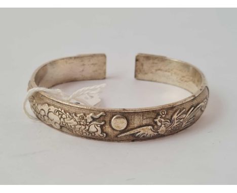A chines silver bangle depicting a dragon chasing a pearl