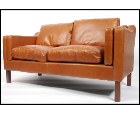 A stunning 1970's style brown leather two seater sofa settee being raised on mahogany square straight feet, in the manner of 