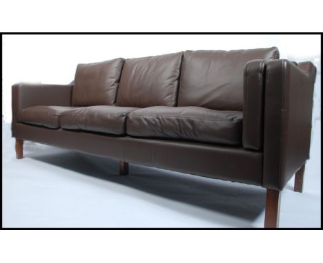 A stunning 1970's style brown leather large three seater sofa settee being raised on mahogany square straight feet, in the ma