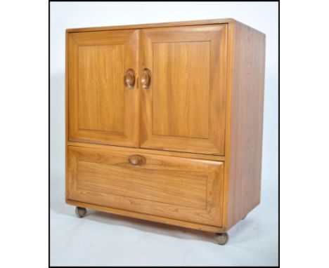 An Ercol 20th century light elm wood ' Windsor ' pattern serving / entertainment cabinet - cupboard. Raised on ball castors w