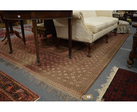 A large Afghan carpet, rust ground with stylised decoration, 350cm x 250cm.