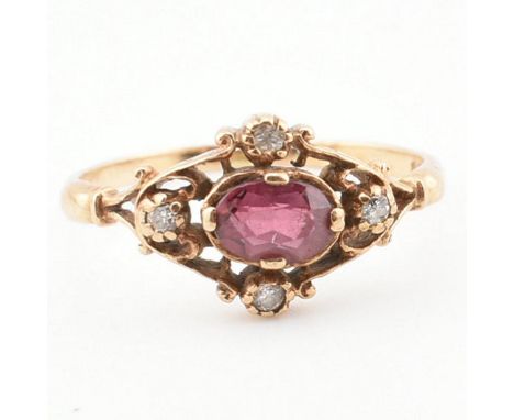 A hallmarked 9ct gold ruby and diamond ring. The ring set with an oval cut ruby framed by a quatrefoil of diamonds to bifurca