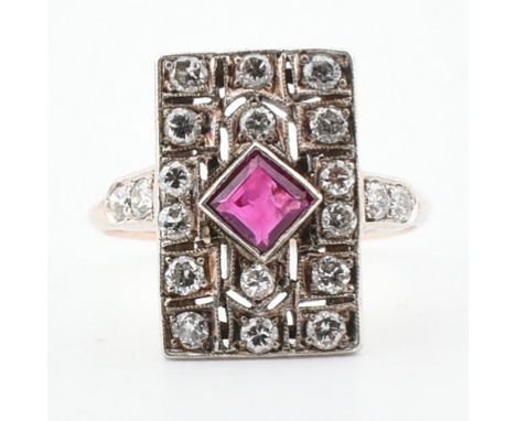 A 1920s ruby and diamond plaque ring. The ring set with a central step cut square ruby framed by a diamond set open work plaq