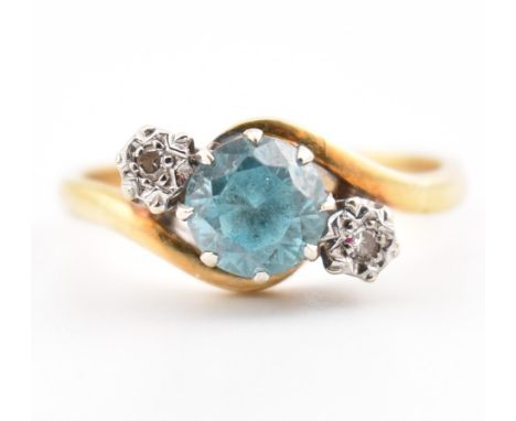 A hallmarked 18ct gold Zircon and diamond ring. The ring set with a blue round cut zircon flanked by two illusion set diamond