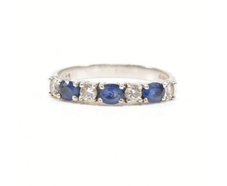 A hallmarked 18ct white gold, diamond and sapphire ring. The ring having four round cut diamonds spaced by round cut blue sap