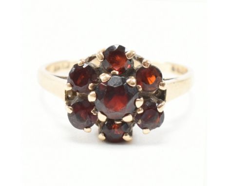 A vintage hallmarked 9ct yellow gold and garnet cluster ring. The ring having a central round cut red stone surrounded in a h