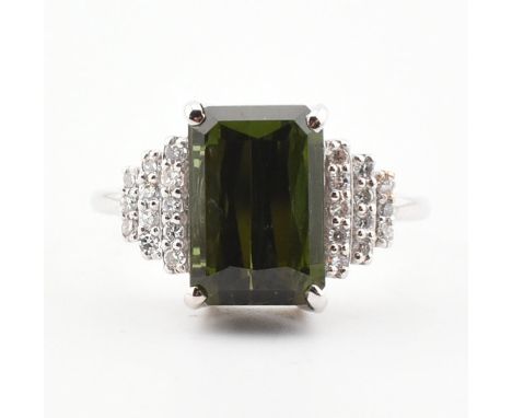 An 18ct white gold, diamond and green tourmaline ring. The ring set with a step cut green tourmaline flanked by diamond set t