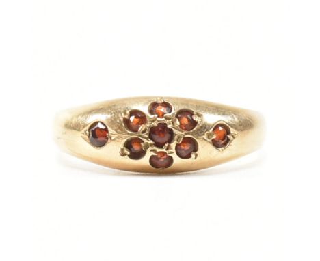 A hallmarked 9ct yellow gold and garnet dome ring. The gypsy style ring having a cluster of round cut garnets to form a flowe