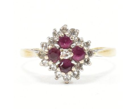 A hallmarked 18ct yellow gold, ruby and diamond cluster ring. The ring having a central round cut diamond in a halo of round 