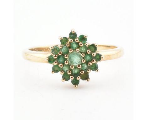 A gold and emerald cluster ring. The ring having a central cluster of round mixed cut emeralds to plain band. Unmarked, tests