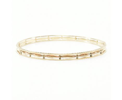 An antique 9ct yellow gold bangle armlet. The cuff arm band of faceted circular form having zigzagged detailing to the rims a
