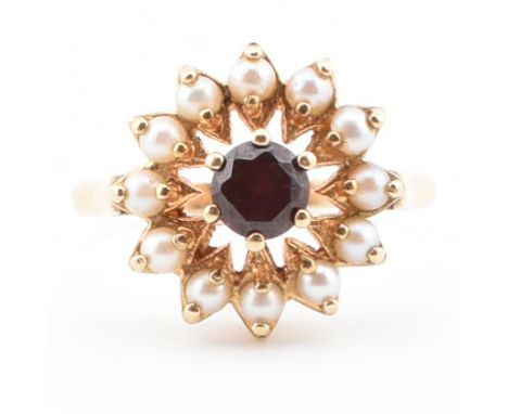 A hallmarked 9ct gold, garnet and pearl cluster ring. The ring set with a central garnet surrounded by pearls to plain shank.
