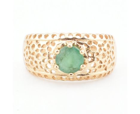 A gold and emerald dome ring. The ring set with a round cut emerald to a pierced domed mount and plain tapering band. Stamped