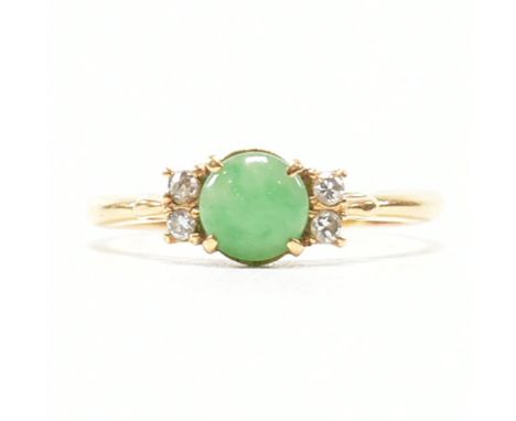 A vintage 18ct yellow gold, jade and diamond ring. The ring having a round cut green stone cabochon flanked by two round cut 