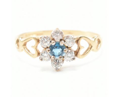 A hallmarked 9ct yellow gold, topaz and cubic zirconia cluster ring. The ring having a central round cut blue topaz surrounde