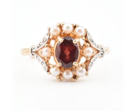 A gold garnet pearl and diamond halo ring. The ring set with a central on oval cut garnet framed by pearls having diamond bif
