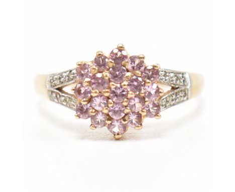 A gold pink stone and diamond cluster ring. The ring set with a pink stone cluster having bifurcated diamond set shoulders. S