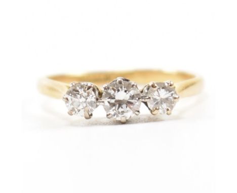 A 18ct gold and platinum three stone diamond ring. The ring set with three graduating round brilliant cut diamonds to a plain