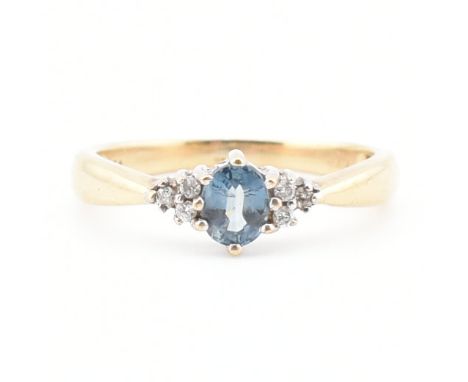 A vintage topaz and diamond yellow metal ring. The ring having a central oval cut blue topaz flanked by a trio of accent diam