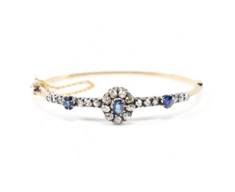 A 1920s sapphire and diamond cluster bangle. The bangle having a central sapphire and diamond cluster having further line of 