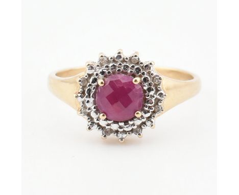 A vintage 9ct yellow gold, ruby and diamond halo ring. The ring having a central round cut ruby surrounded in a cluster of ro