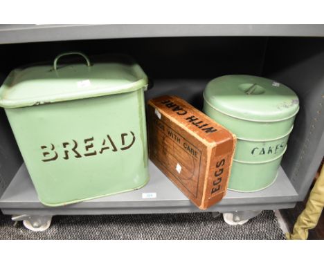 A mid-20th Century green enamelled bread bin, measuring 36cm high, together with an enamelled cake tin of similar age, and an