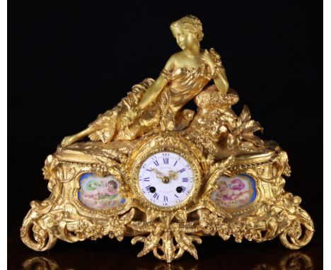 A 19th Century Gilt Metal Mantel Clock surmounted by the figure of a reclining lady above a round enamel dial signed Prunier 