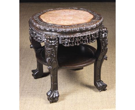 A Chinese Carved Hardwood Table/ Stand.  The petalled top with pink marble insert in a carved border of undulating flowers an