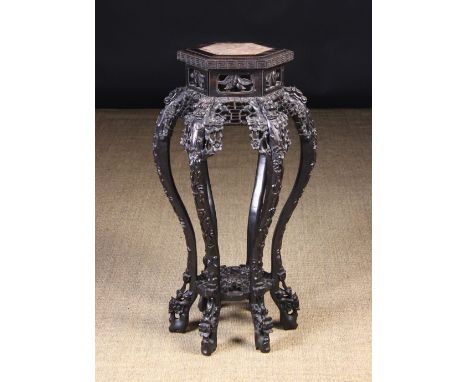A Late 19th Century Chinese Carved Hardwood Plant Stand.  The hexagonal top with pink marble inset above a pierced frieze and
