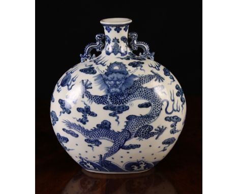 A Chinese Blue & White Moon Flask decorated with dragons chasing a flaming peal amidst wisps of scrolling clouds, and having 