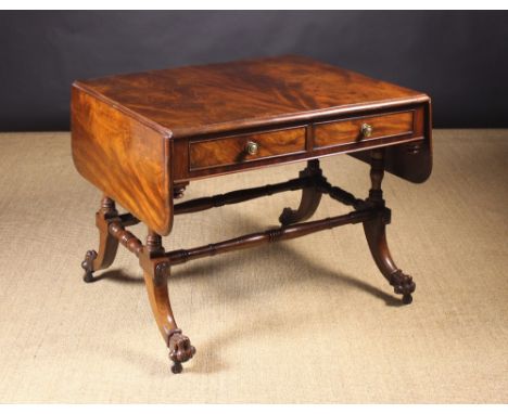 A Fine Regency Mahogany Sofa Table. The flame figured top having rounded end flaps on fly brackets and a moulded edge above f